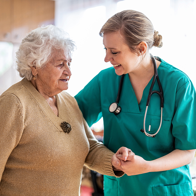 smiling nurse holding elderly woman's hand